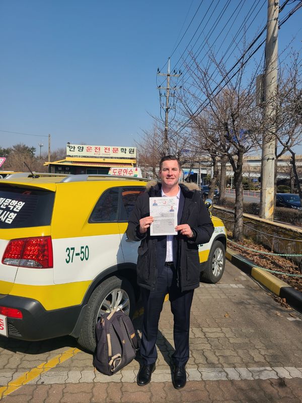 International student celebrating a road driving test pass at Anyang Driving School