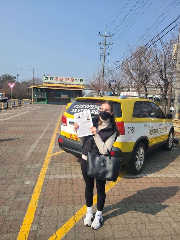 Foreign student holding a newly issued Korean driver's licence at Anyang Driving School